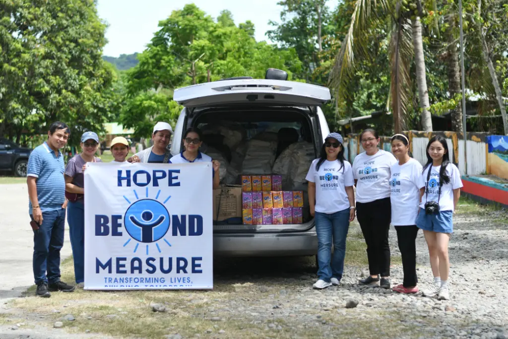 Volunteers with the Hope Beyond Measure banner unloading supplies from a van
