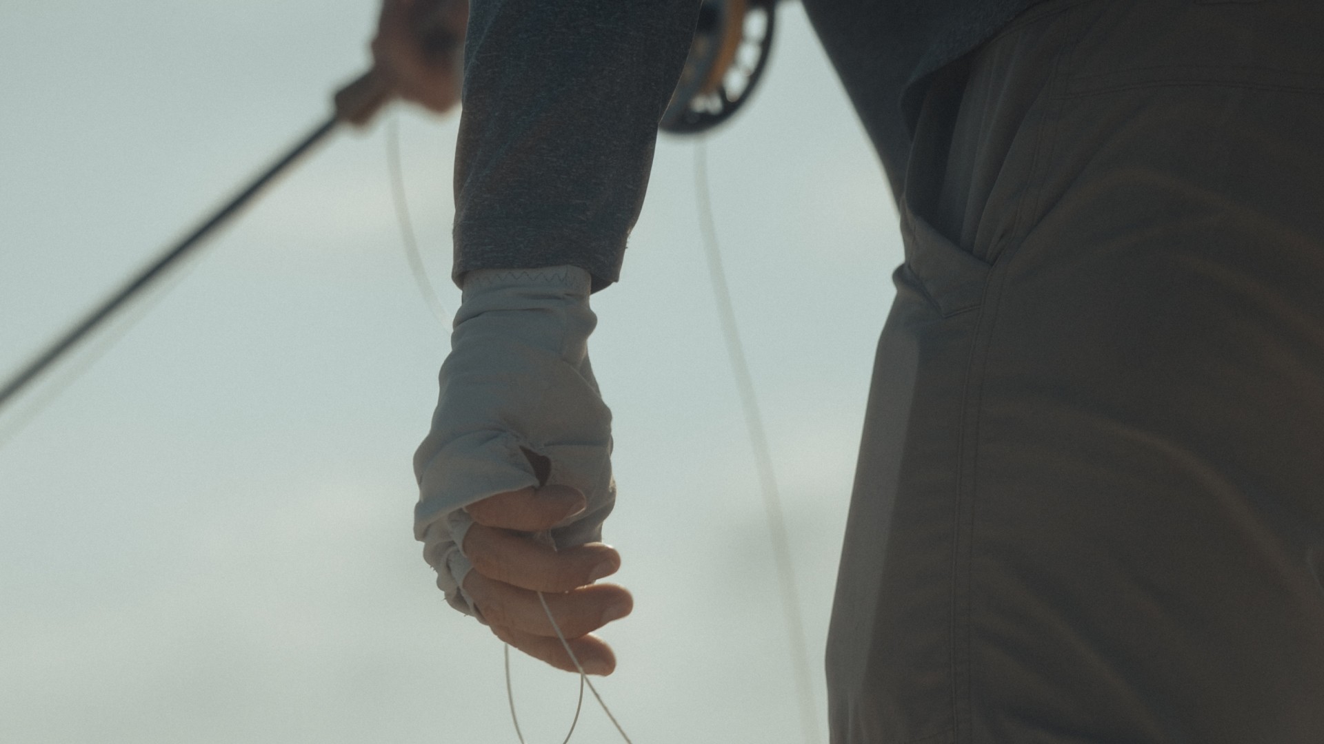 Person holding a fishing rod and retrieving fly line