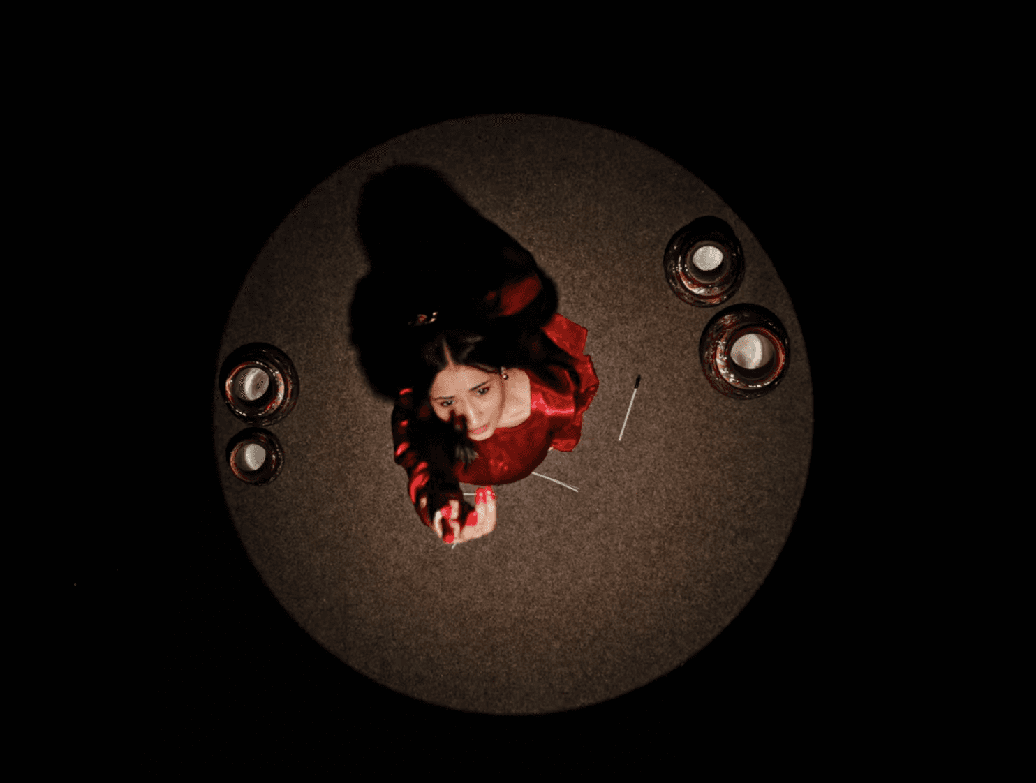 Cinematic overhead shot of a south asianwoman in a red outfit seated at a round table with traditional metal bowls.