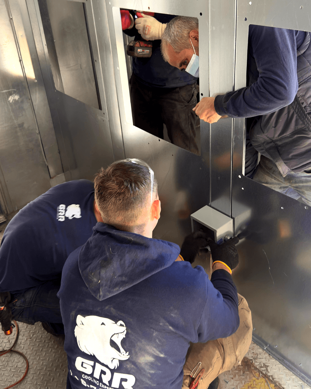 GRR Cooling Experts technicians removing a legacy fan assembly inside a hospital air handling unit during live retrofit work.