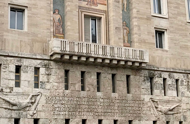 A photo of a stone building that has sculptures and embossed text on it.