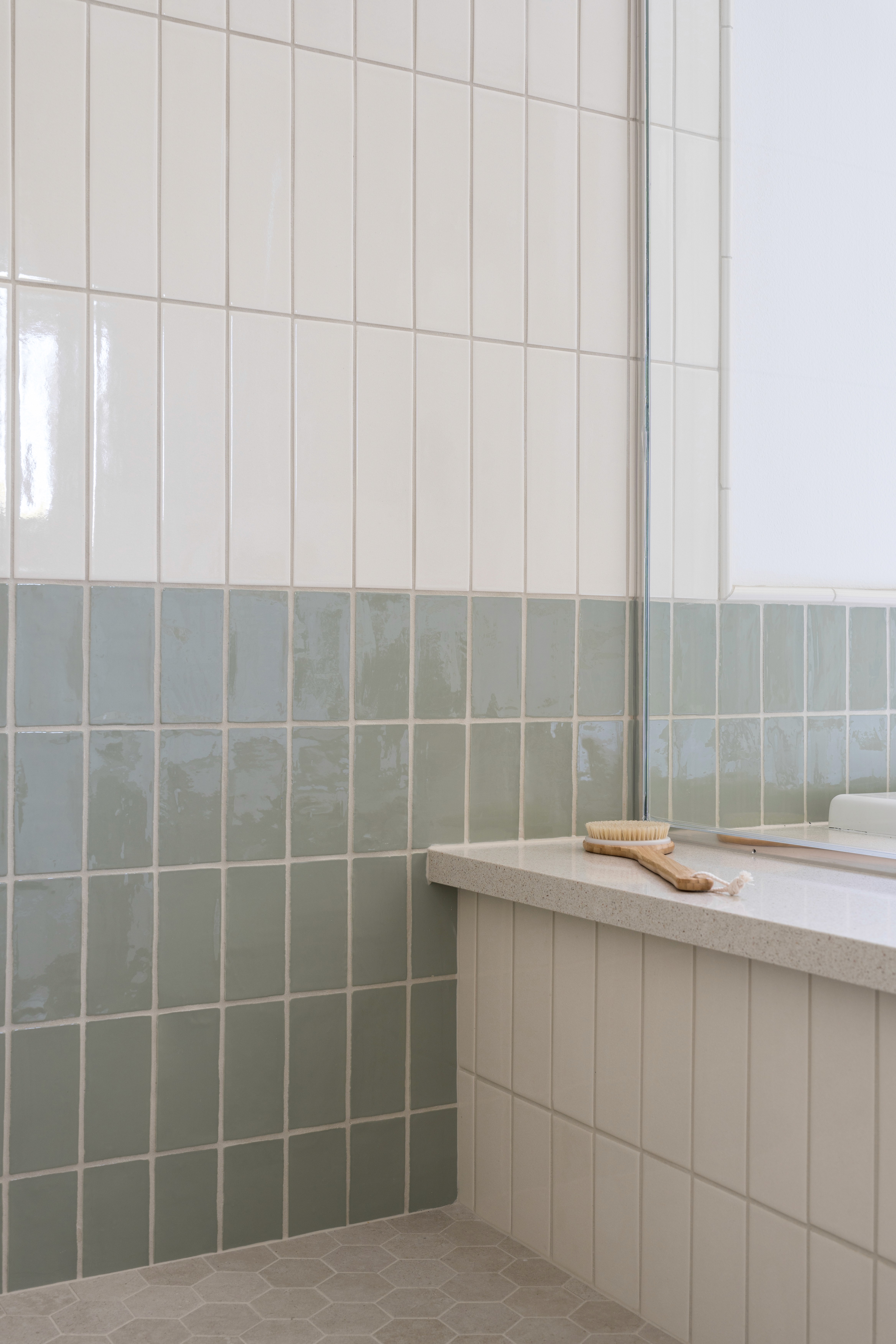 Bathroom shower with two-thirds white tile and sage green tile on bottom third and shower bench by Jubilee Interiors in Arcadia, California