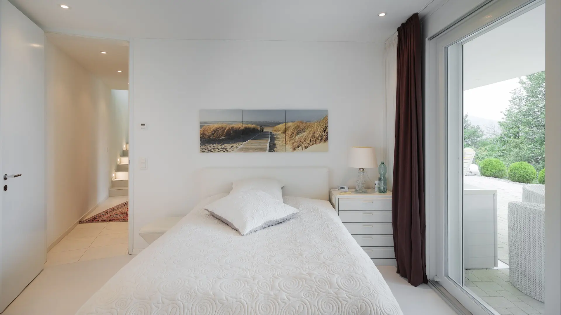 Stilvolles Schlafzimmer in hellen Farbtönen mit Kunstbild über dem Bett