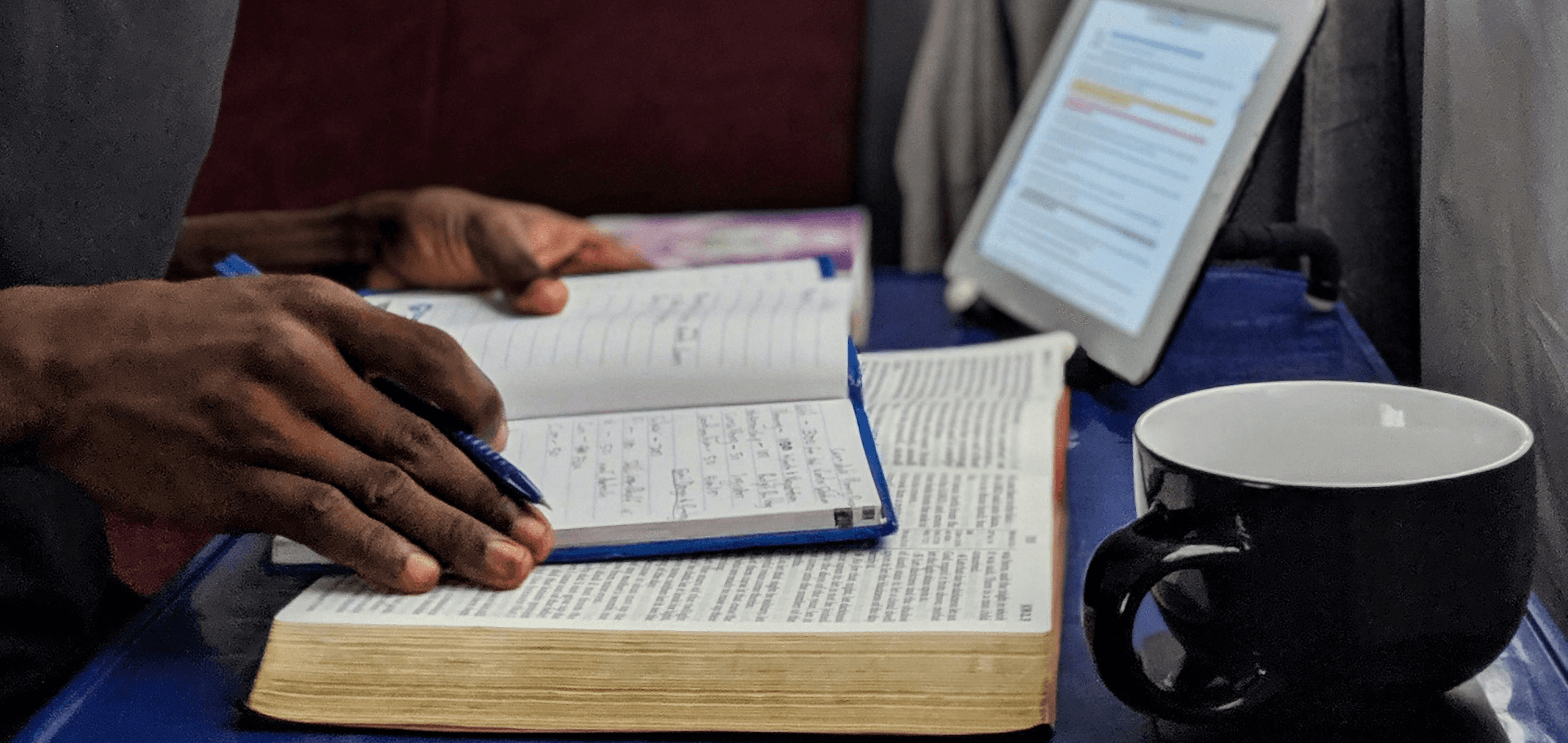 Person writing notes near a book - How Many Sources Should Be In A Literature Review