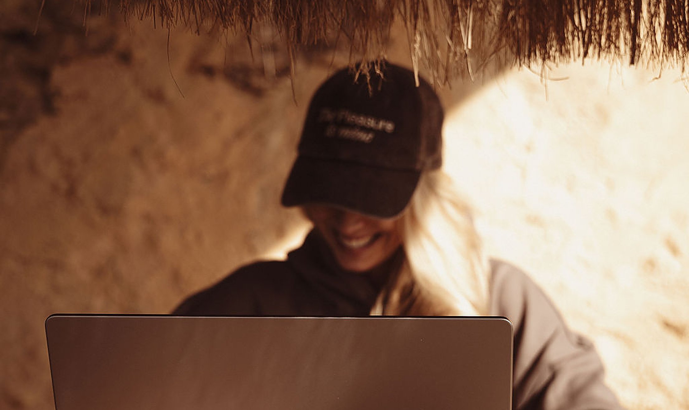 Woman smiling at her laptop in a cozy private corner, taking an online intimacy course in her own time at home | My Temple