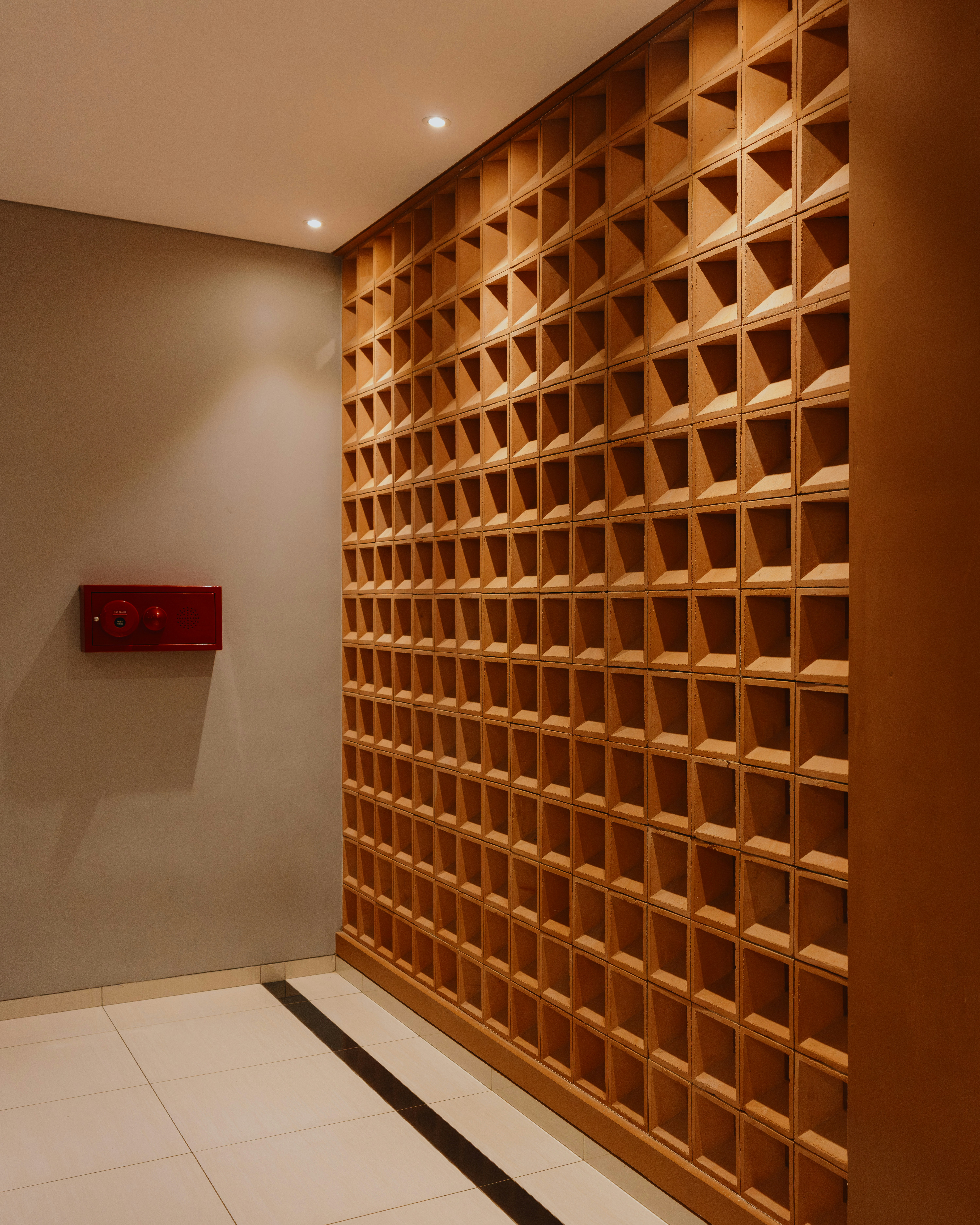 Geometric wooden wall with square openings and red box.