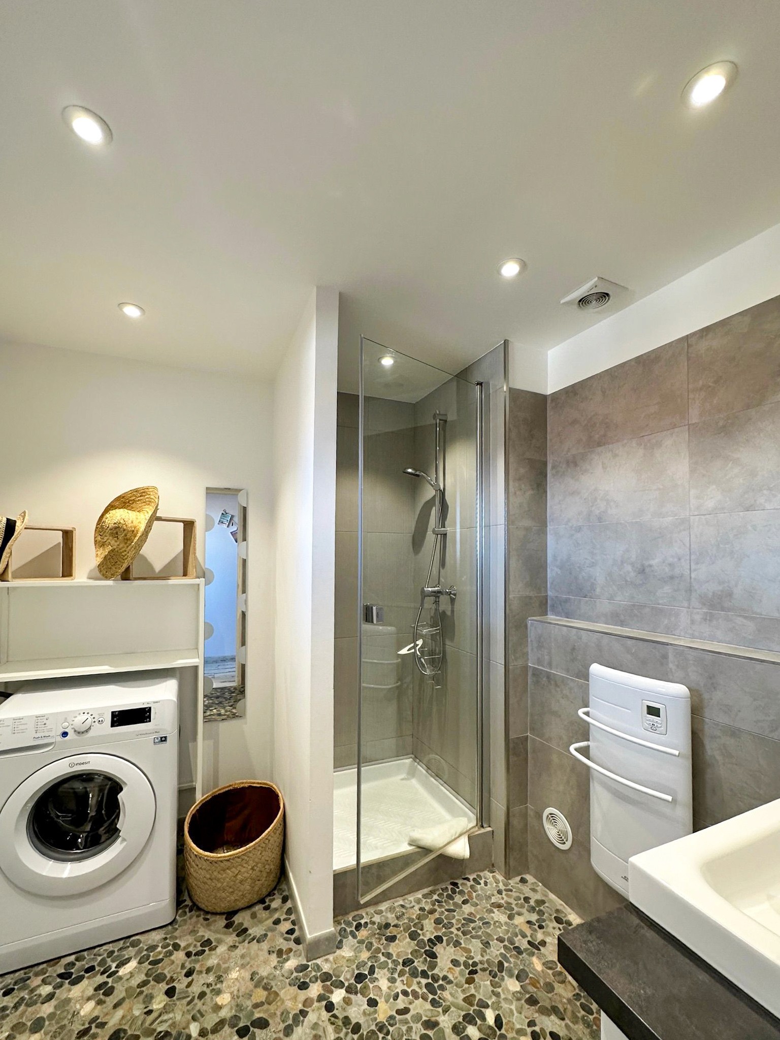 Meuble vasque suspendu en bois avec miroir rétroéclairé LED et crédence en pierre naturelle.