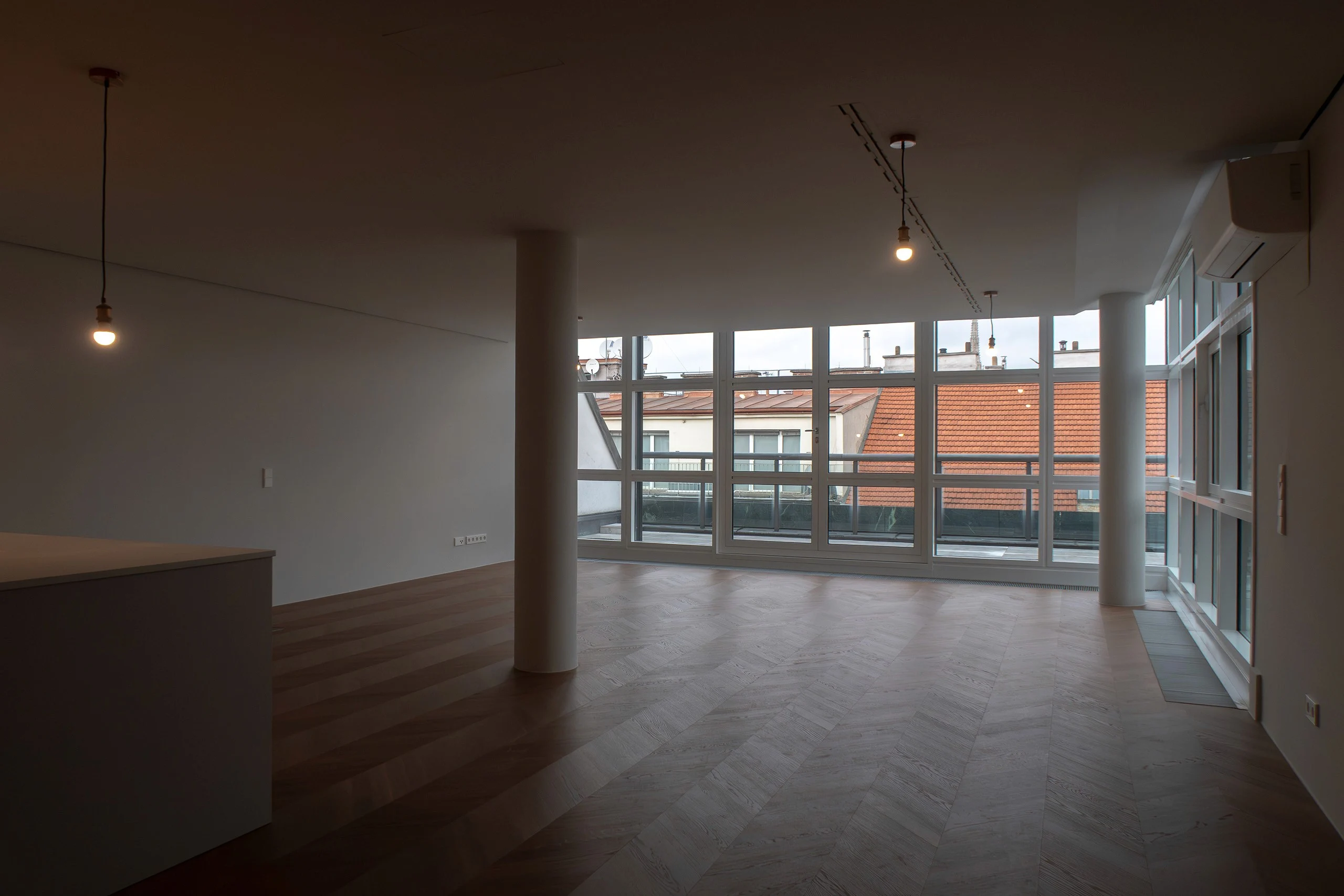 Moderner Wohnraum mit großer Fensterfront und frisch verlegtem Fischgrät-Parkettboden