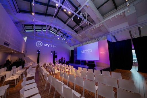 A spacious event hall with rows of chairs, colorful lighting, and a stage in the background.