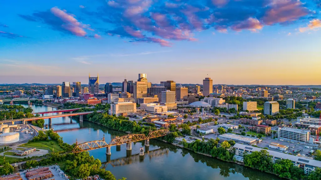 Nashville skyline silhouetted against a vibrant sunset, showcasing tall buildings and a colorful sky.