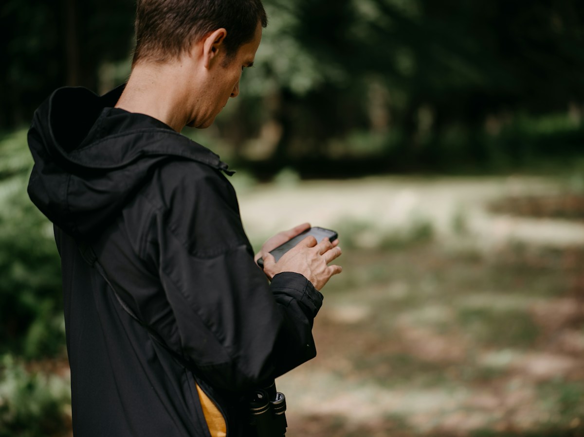A traveler checking their phone in a forest setting