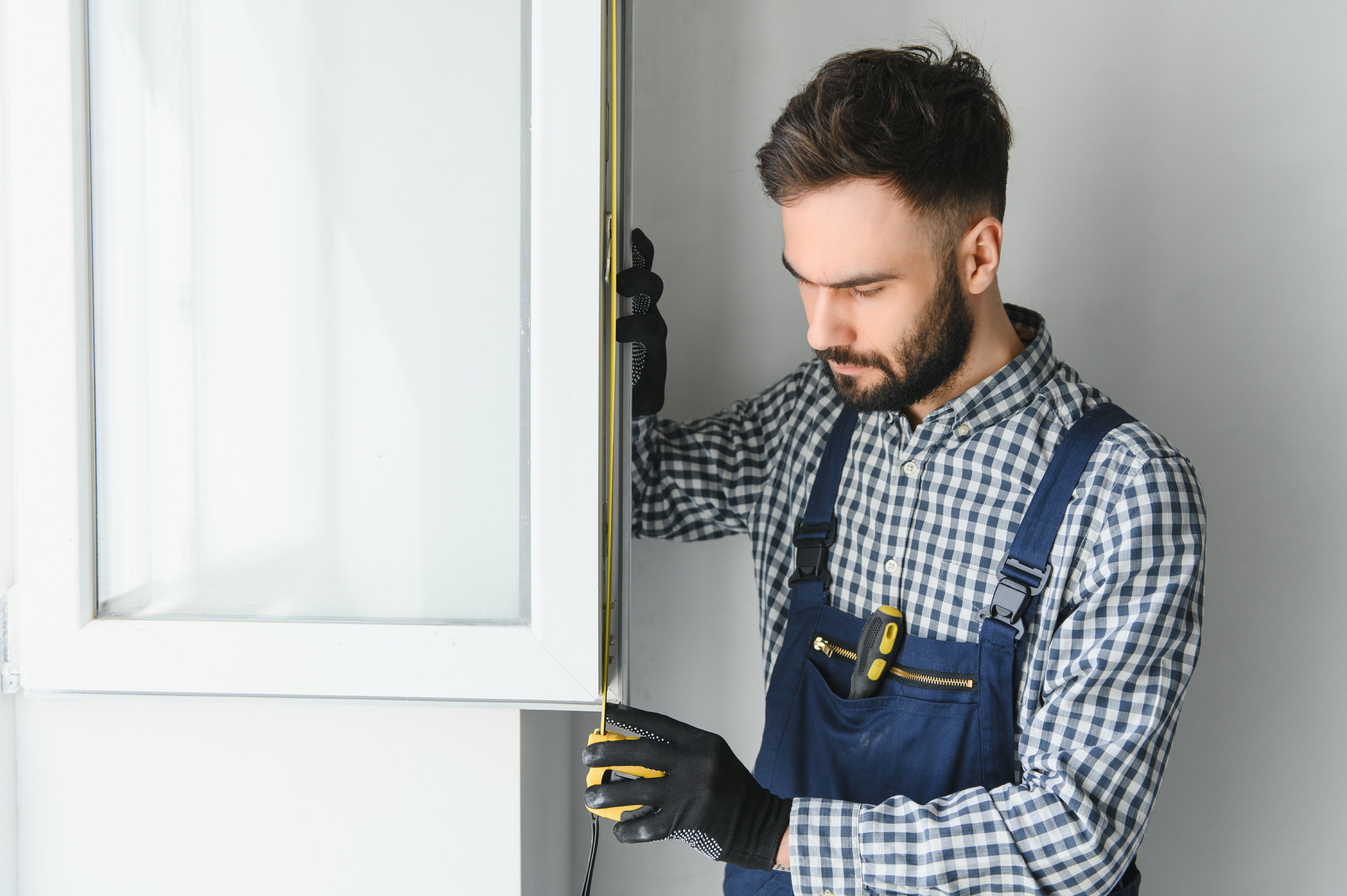 Worker in a checkered shirt installing a door frame.