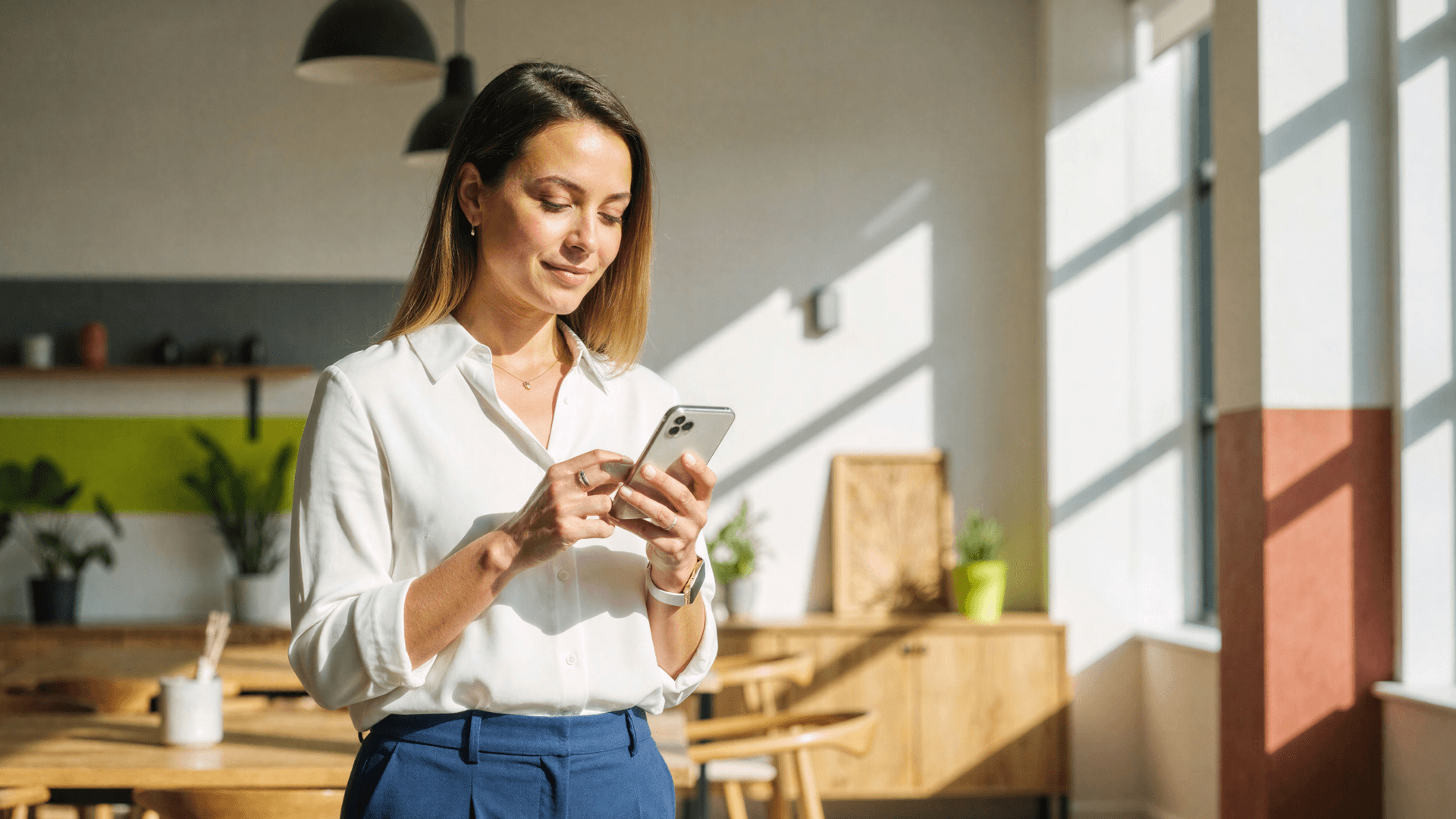 Mulher usando smartphone em ambiente profissional iluminado, representando a digitalização da comunicação em clínicas com a Tivita.