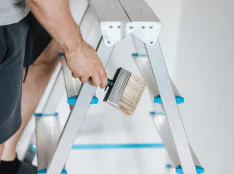 Painter climbing a ladder with paint brush