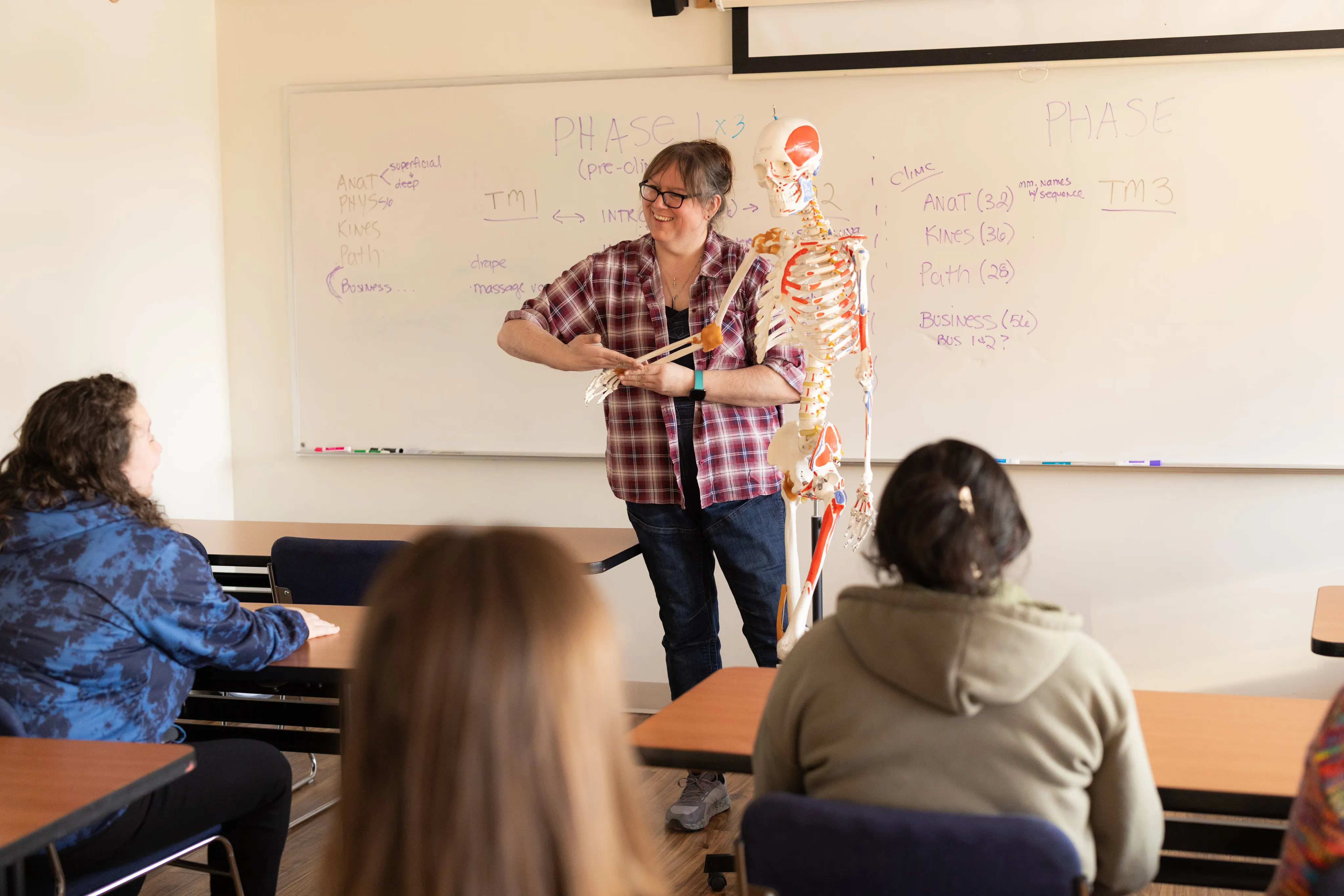 Instructor teaching anatomy to massage therapy students in a classroom at Body Wisdom School.