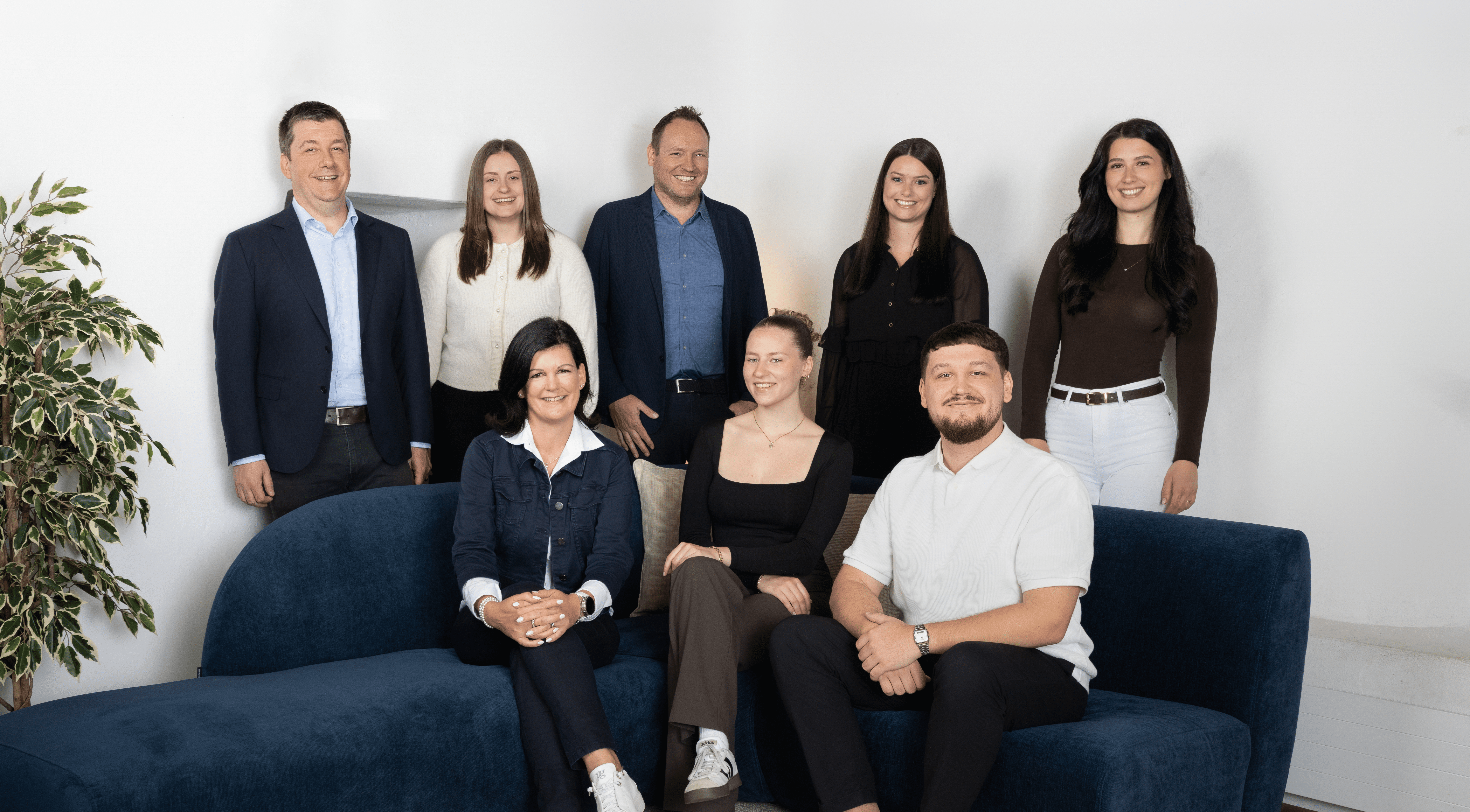 Gesamtes Team von Kocher Immobilien sitzt gemeinsam im Büro und lacht in moderner Umgebung