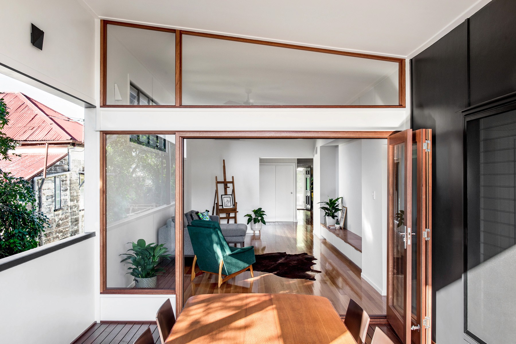 Glazed transition space at Oxford Cottage, where operable timber doors and internal windows connect the original cottage to the contemporary extension.
