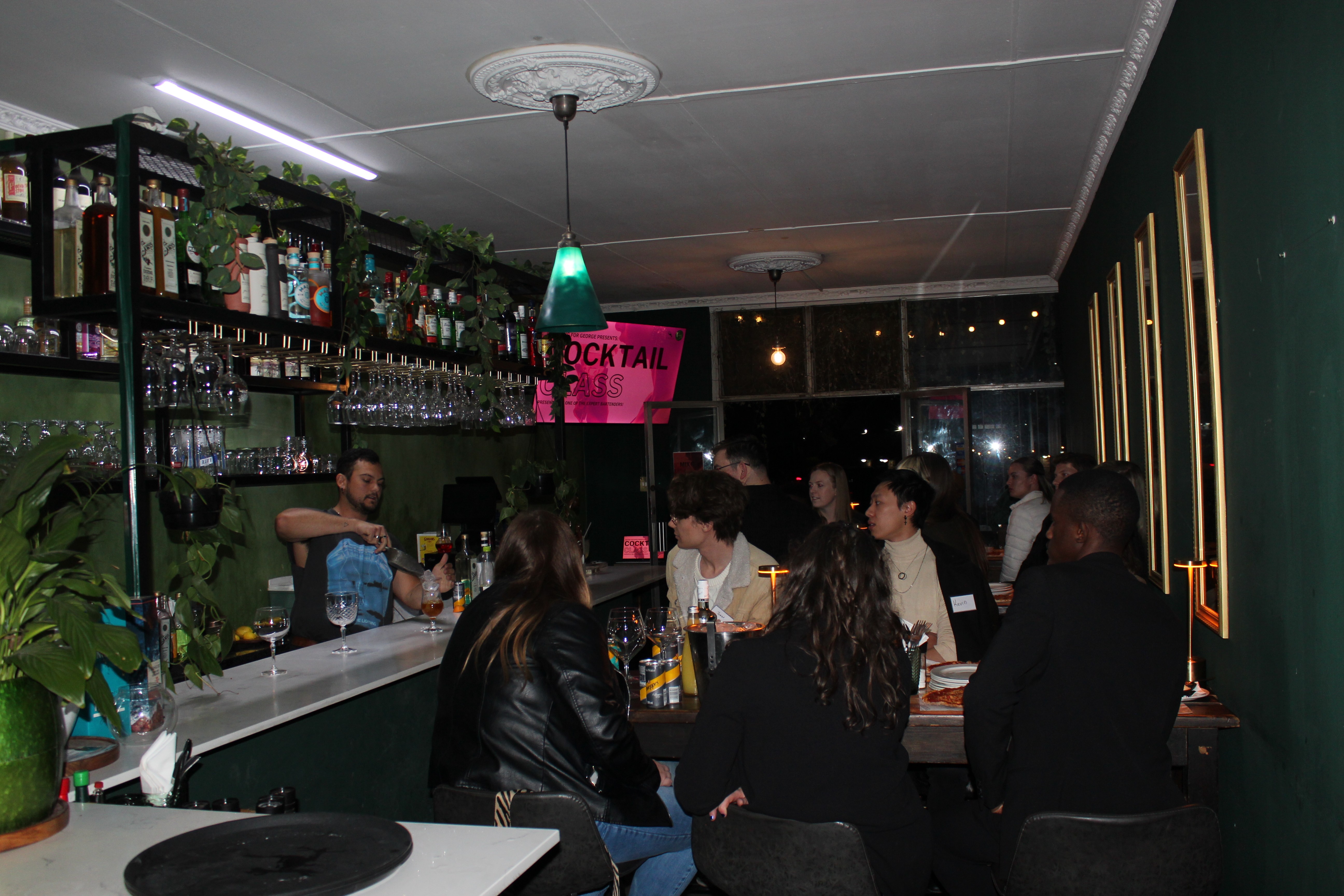 A group of people at a bar watching the bartender