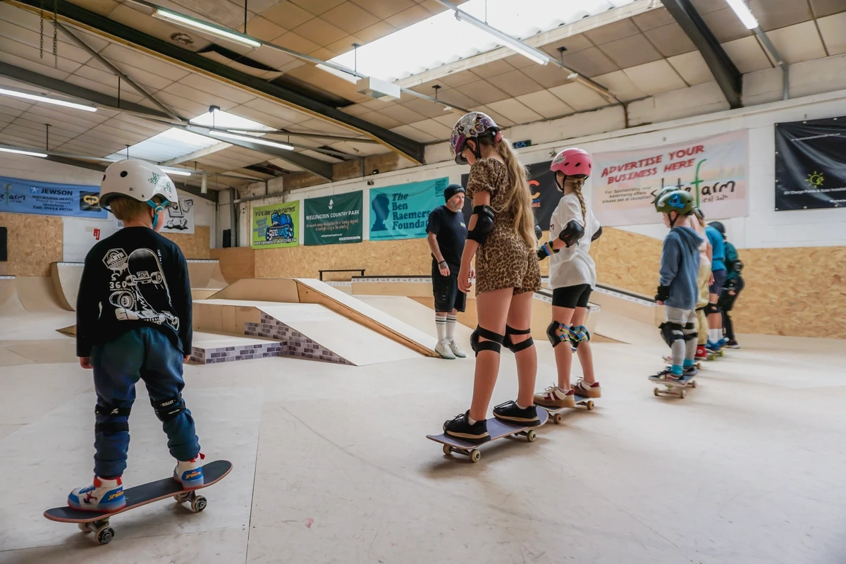 A group of children wearing helmets and protective gear ready to skate at The Skate Farm indoor skatepark in Haywards Heath