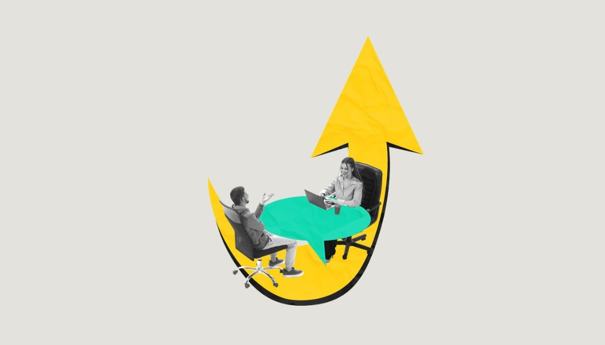 Two professionals at table with laptop inside upward arrow, symbolizing preparation for embedded systems engineer interview.