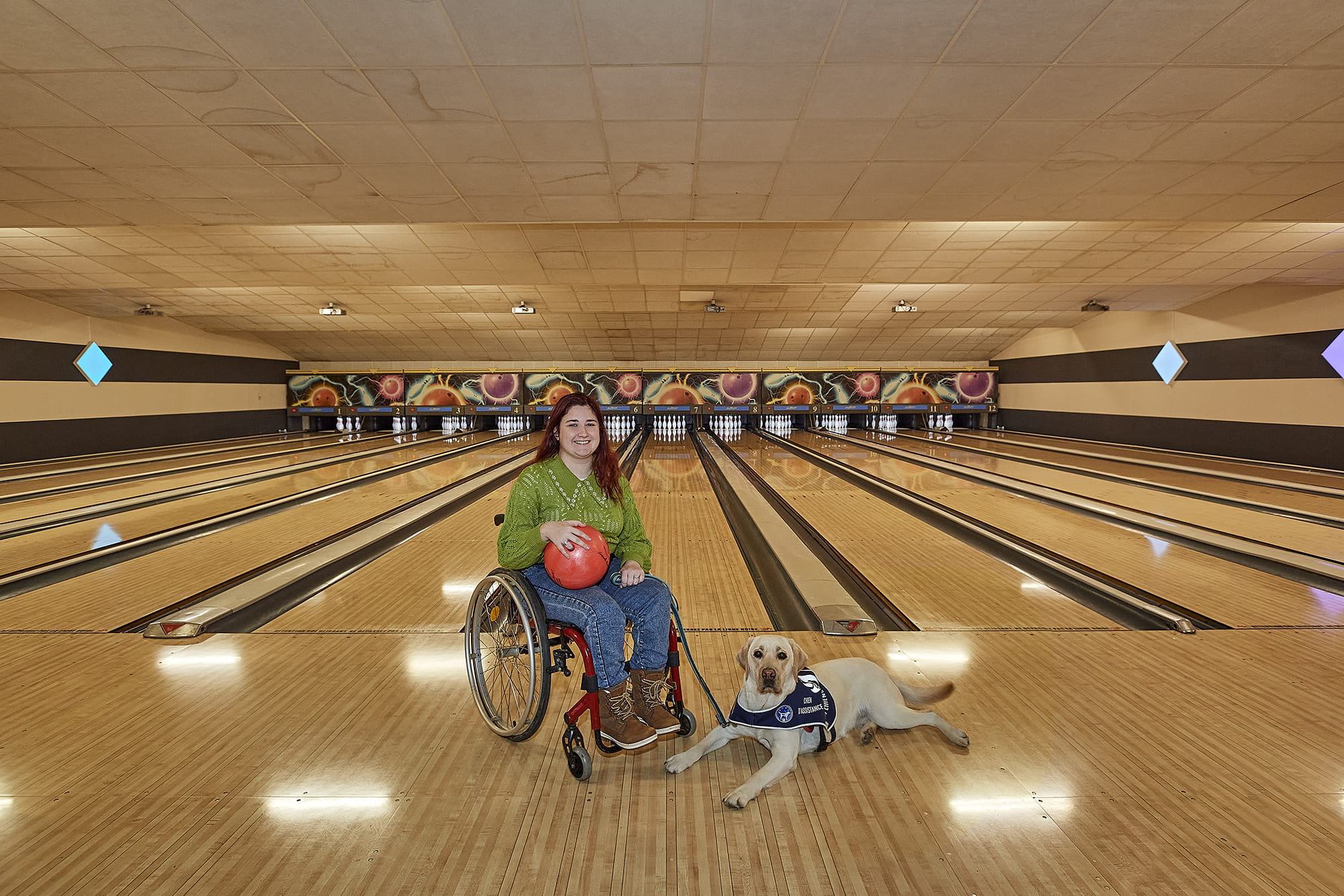 Axelle accompagnée de son chien d’assistance Terra, photographiées par Frédéric Bourcier au Bowling du Brézet à Clermont-Ferrand dans le cadre d’un reportage documentaire social pour Handi’Chiens.