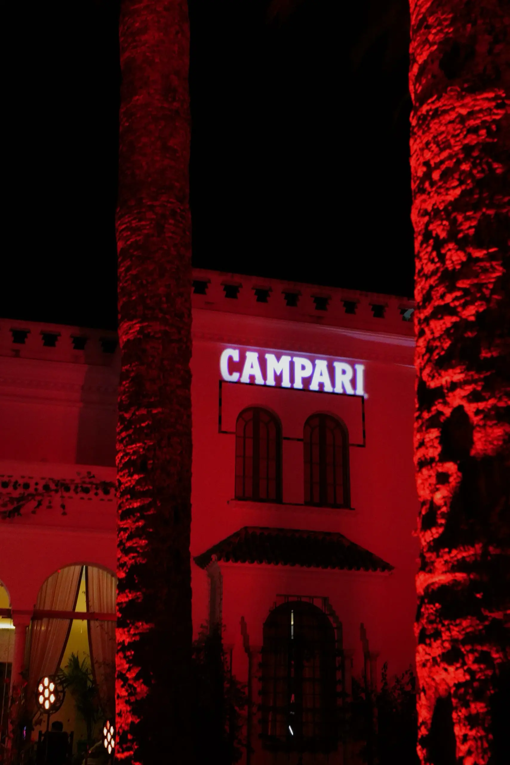 Exterior del evento iluminado con luz roja y letrero blanco de campari