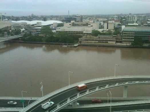 An aerial photo of a canal near a highway on one side and the city scape on the other side.