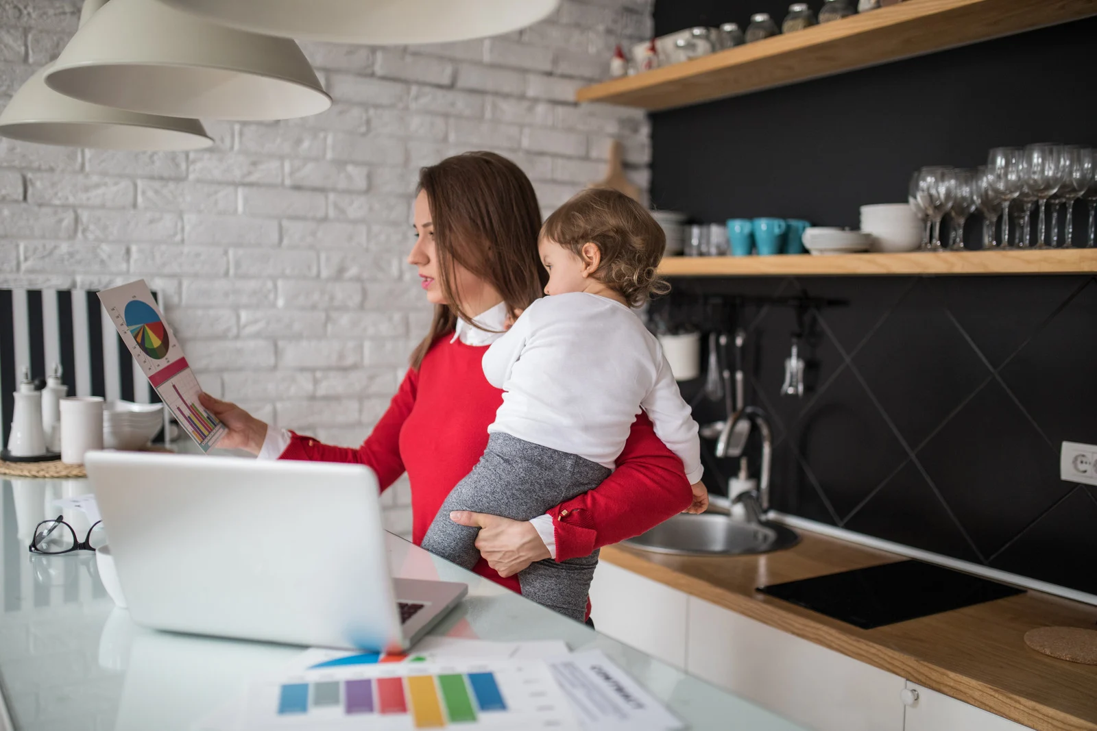 Woman holding a child at home while reviewing insurance documents related to a no claims discount