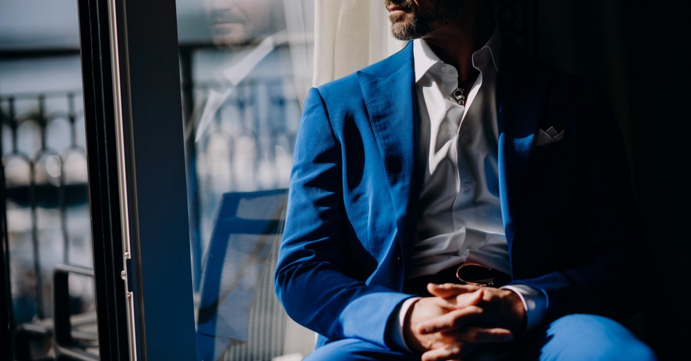Person in a blue suit sitting by a window with the HoustonPlus logo displayed on a smartphone, symbolising leadership and modern technology.