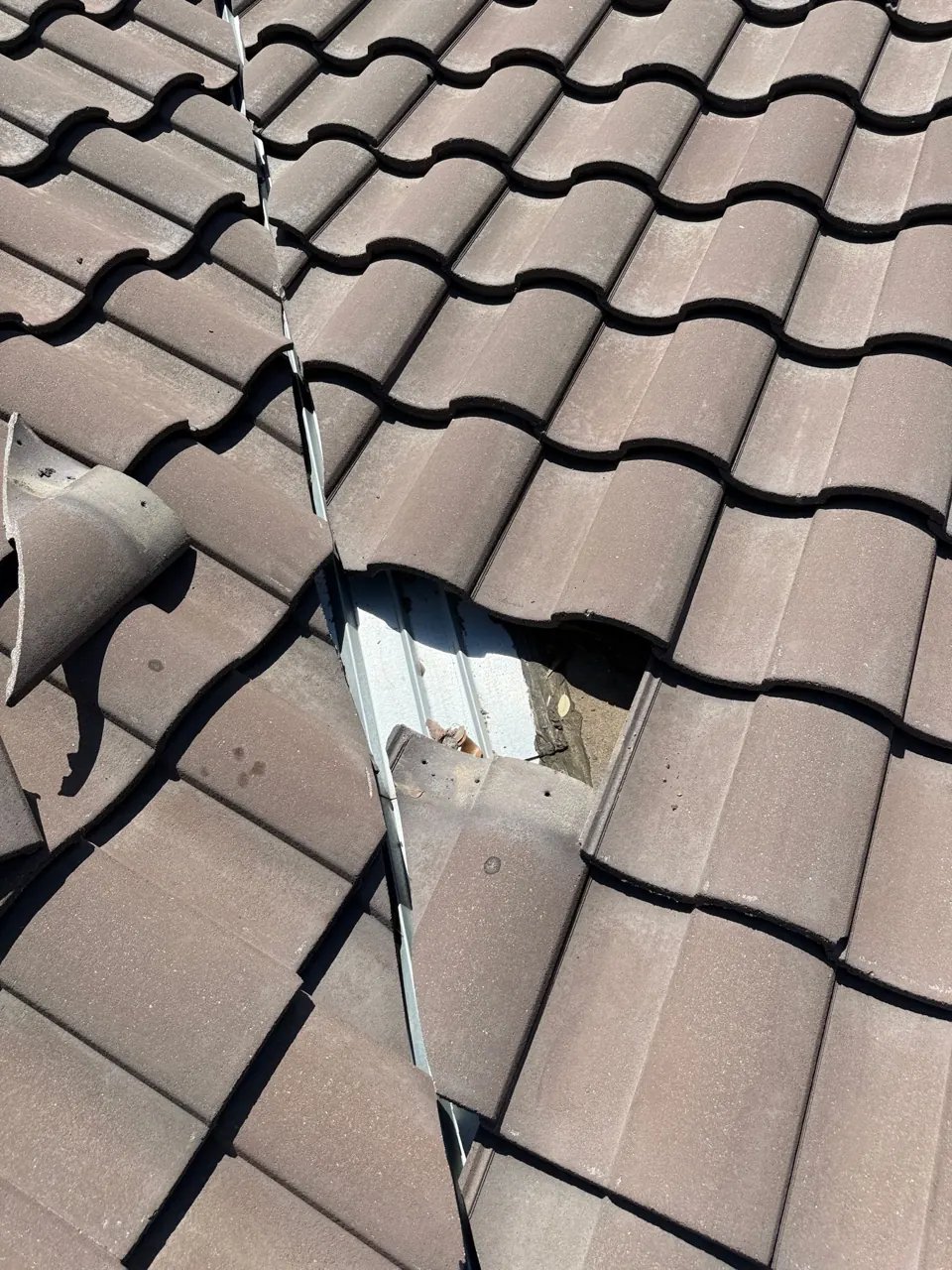 A Georgetown tile roof opened beside a valley, exposing the metal water channel during a documented Barnes N’ Roofs repair.