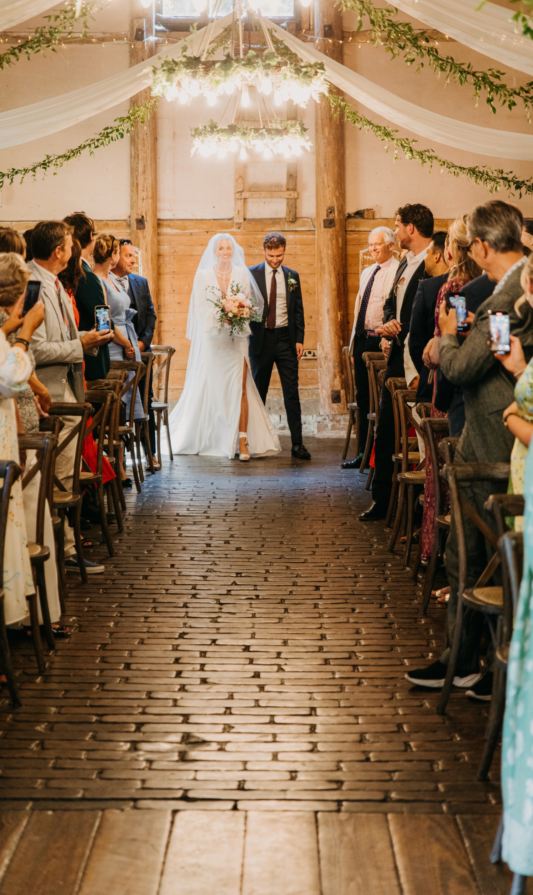 Bride embarks on walk down the aisle during wedding ceremony smiling as congregation looks on