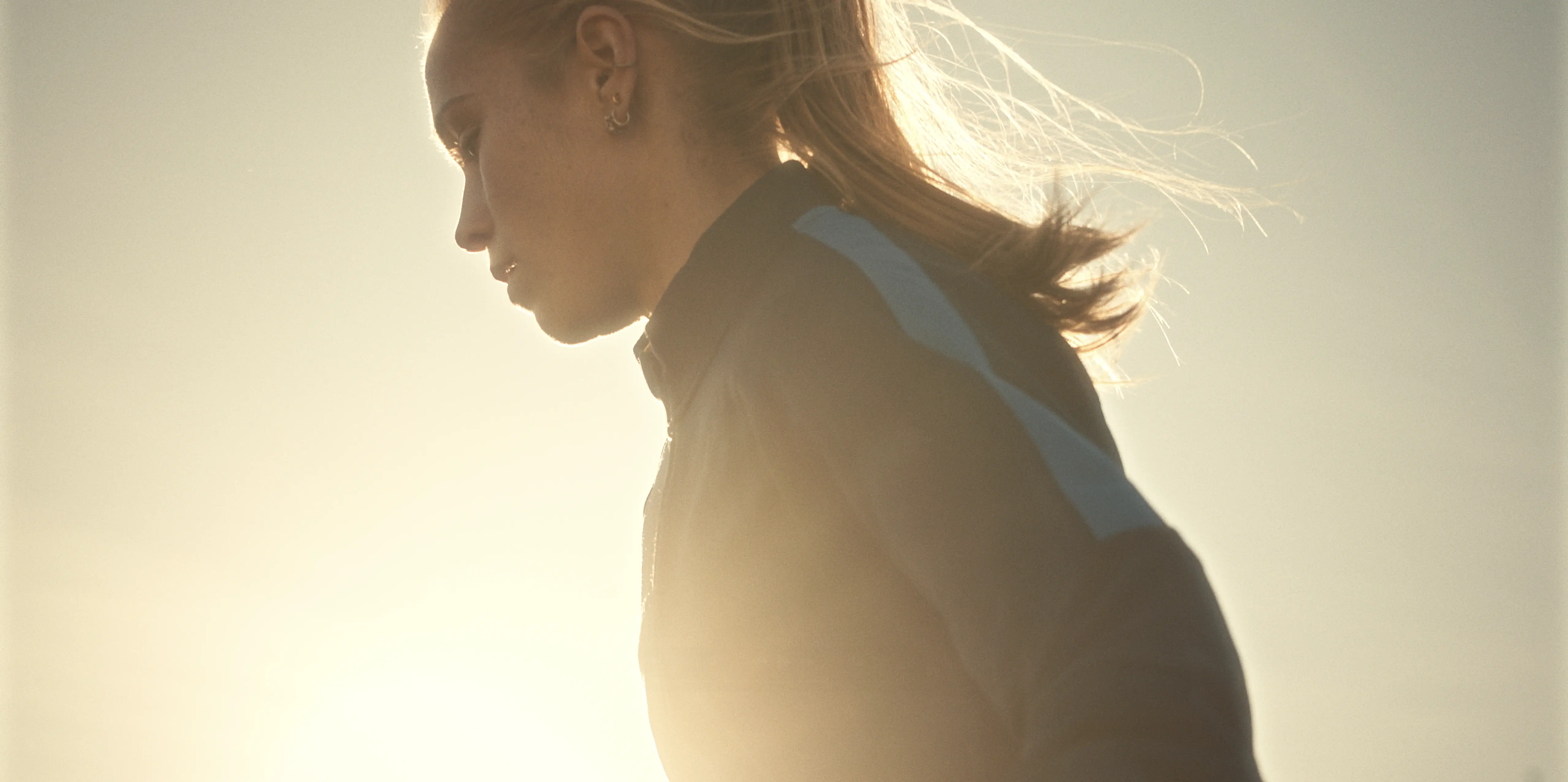 A person in athletic gear jogs outdoors during sunrise, with warm golden light illuminating their silhouette and creating a serene, motivational atmosphere.