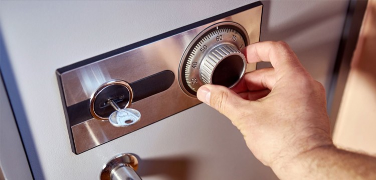 Man inserting a key into a safe and dialing the combination, with the key required to release the dial.