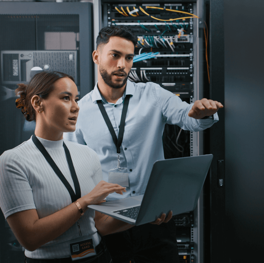 A man and a woman working in a server room