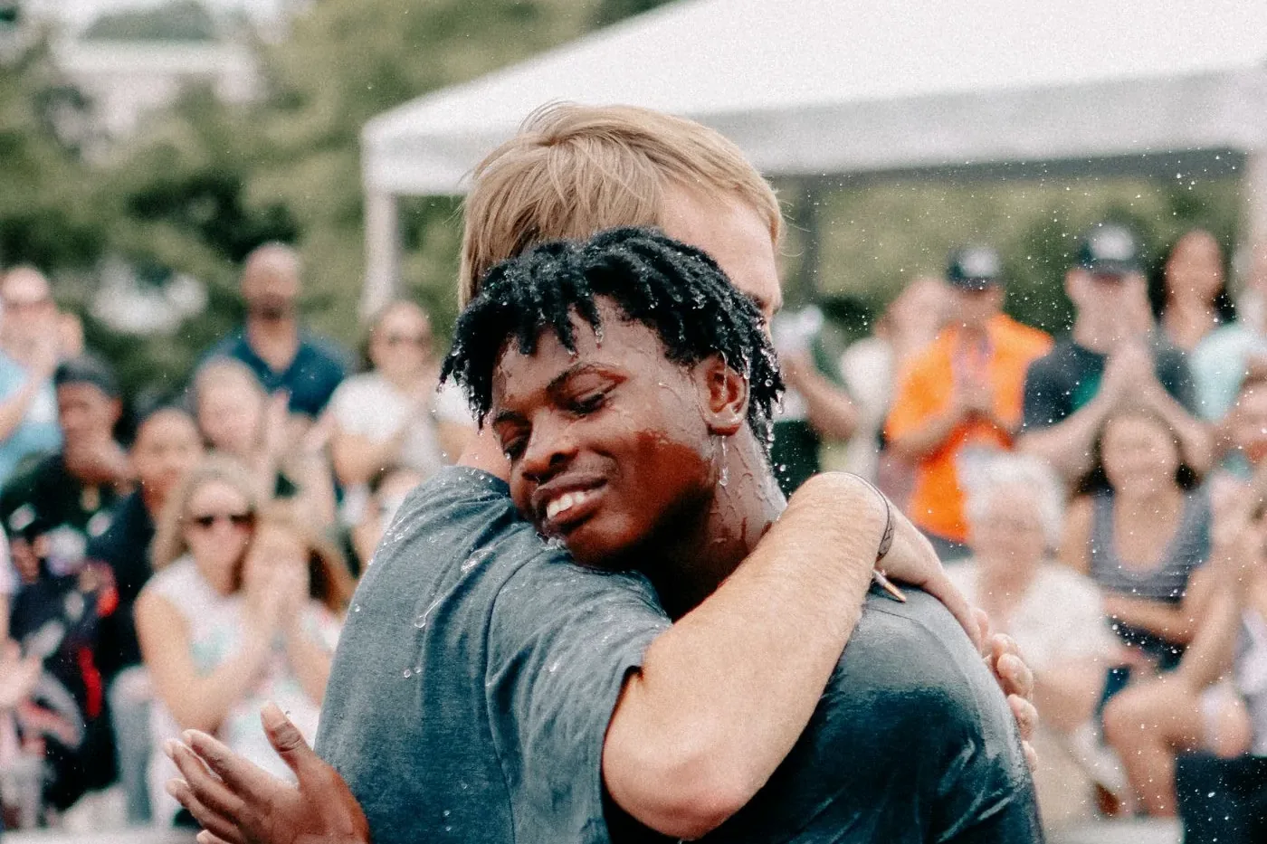 Two friends hugging in the water after a baptism