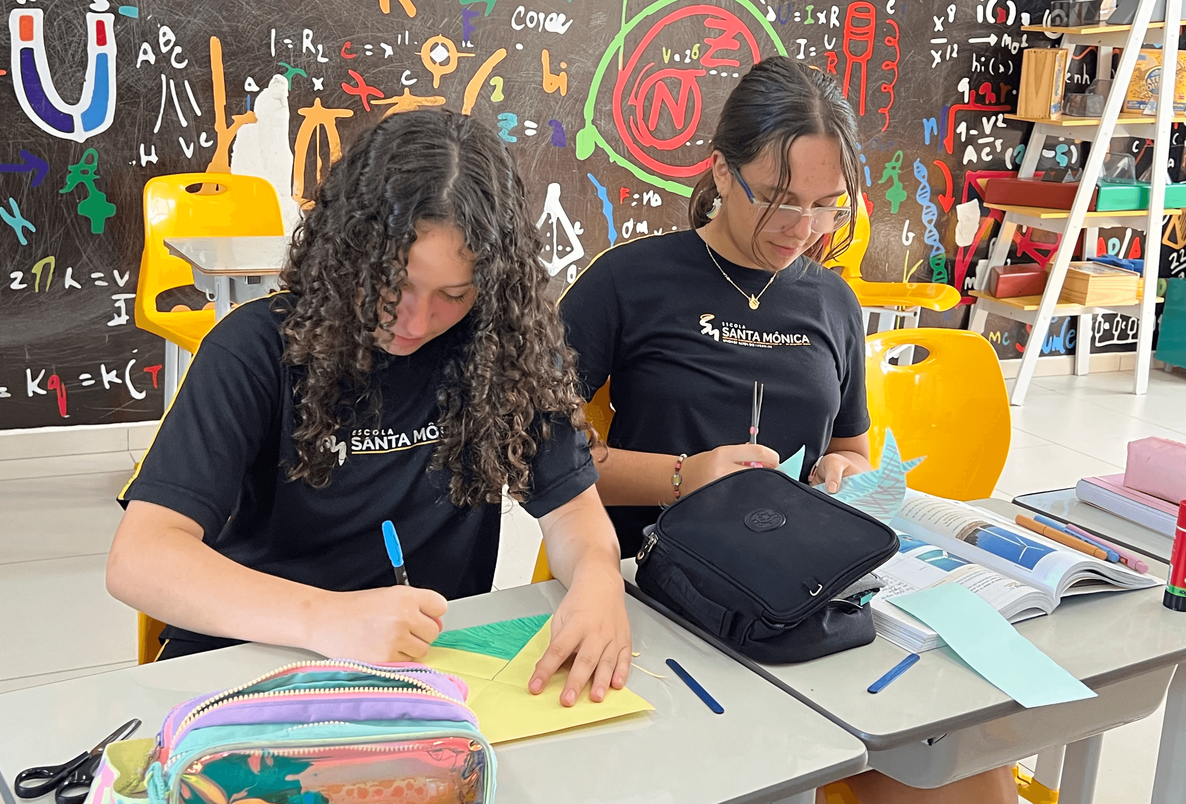 Alunos da Escola Santa Mônica constroem cata-vento em atividade prática para explorar simetria de rotação e movimento rotacional na aula de matemática.