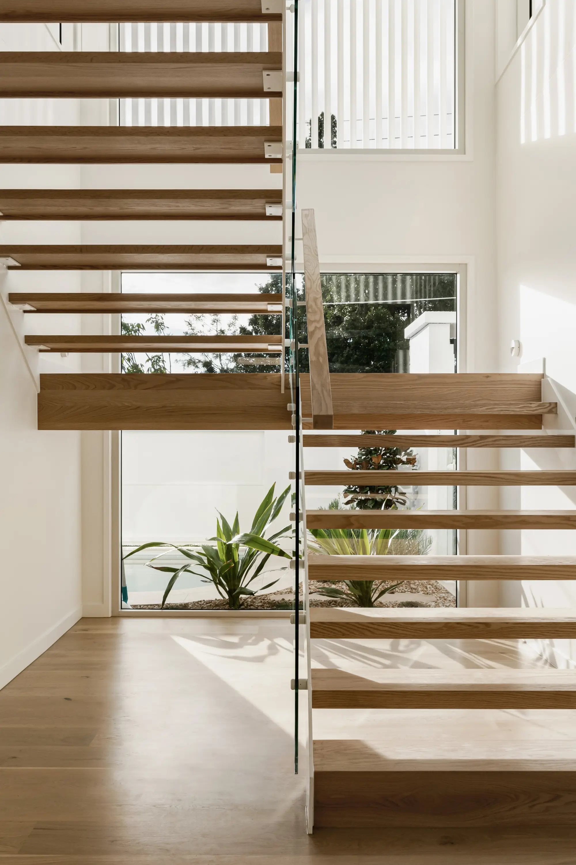 A staircase in front of a large picture window that allows in natural light
