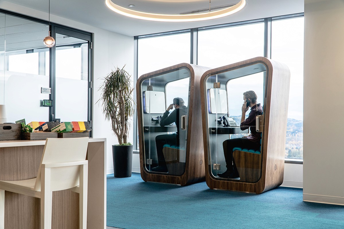 Two people on the phone inside their own privacy pod in modern looking office