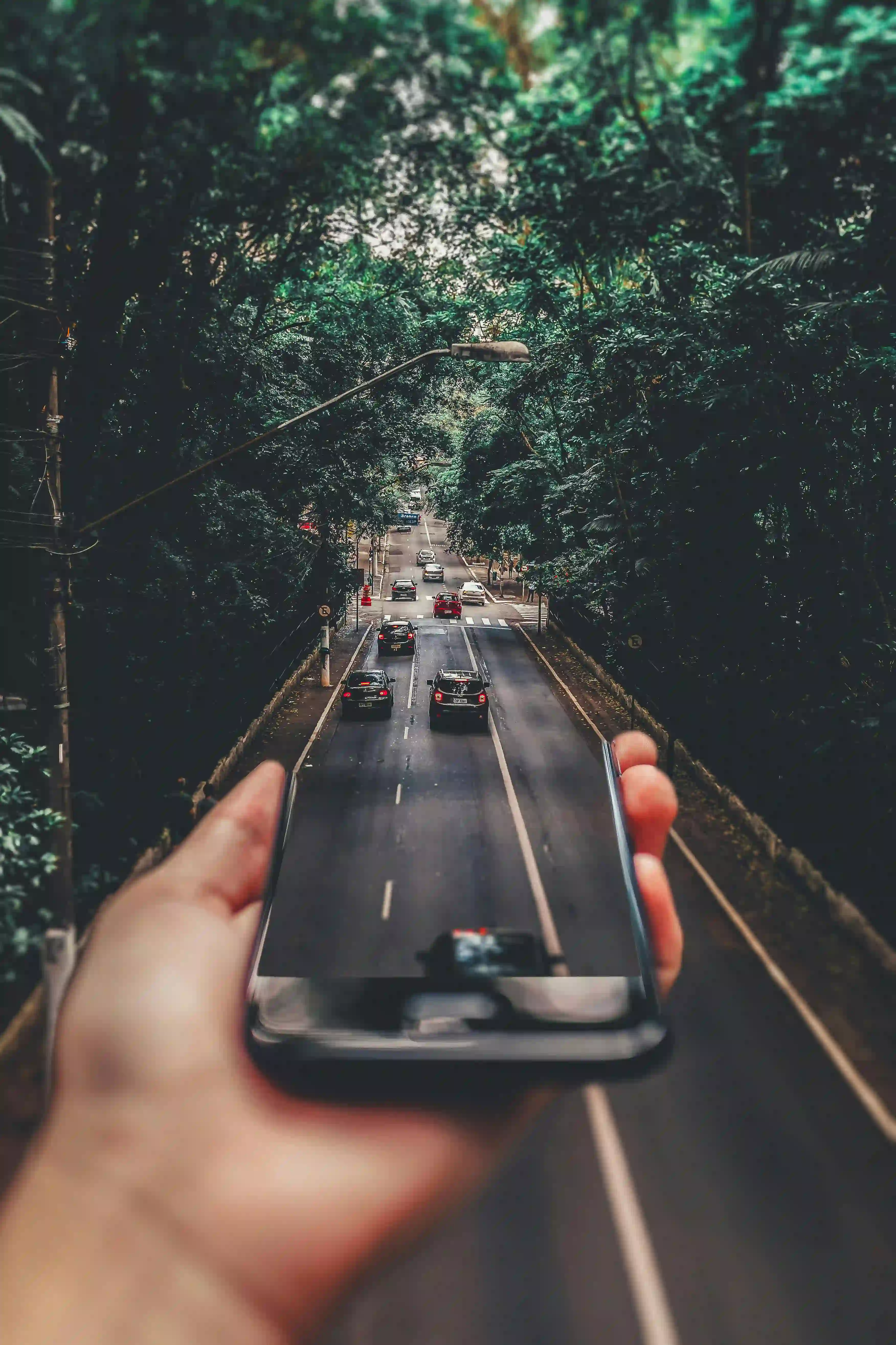 Hand holding phone blending with the road