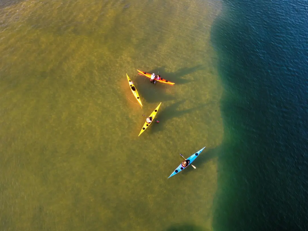 Aerial shot of four kayaksfloating in clear water at golden hour