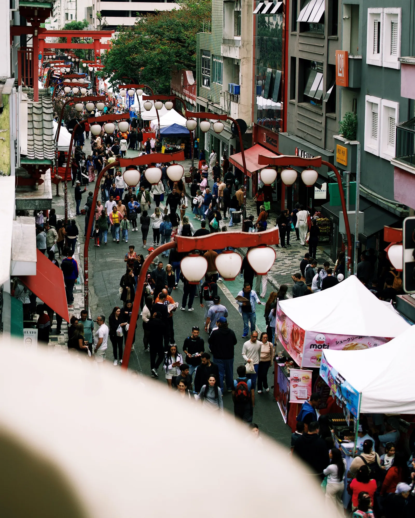 Vista do alto da rua com as lanternas e o torii da Liberdade, a partir de uma das varandas do Janela Viva