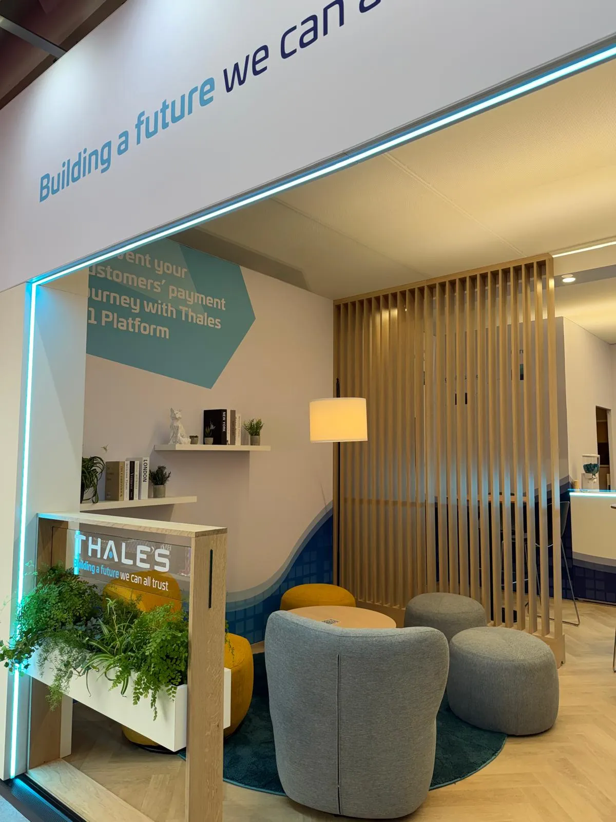 Stand Thales conçu et réalisé par Expace au Money 20/20 Europe Amsterdam – espace sur-mesure avec lounge cosy, claustras bois, jardinières végétalisées et signature « Building a future we can all trust ».
