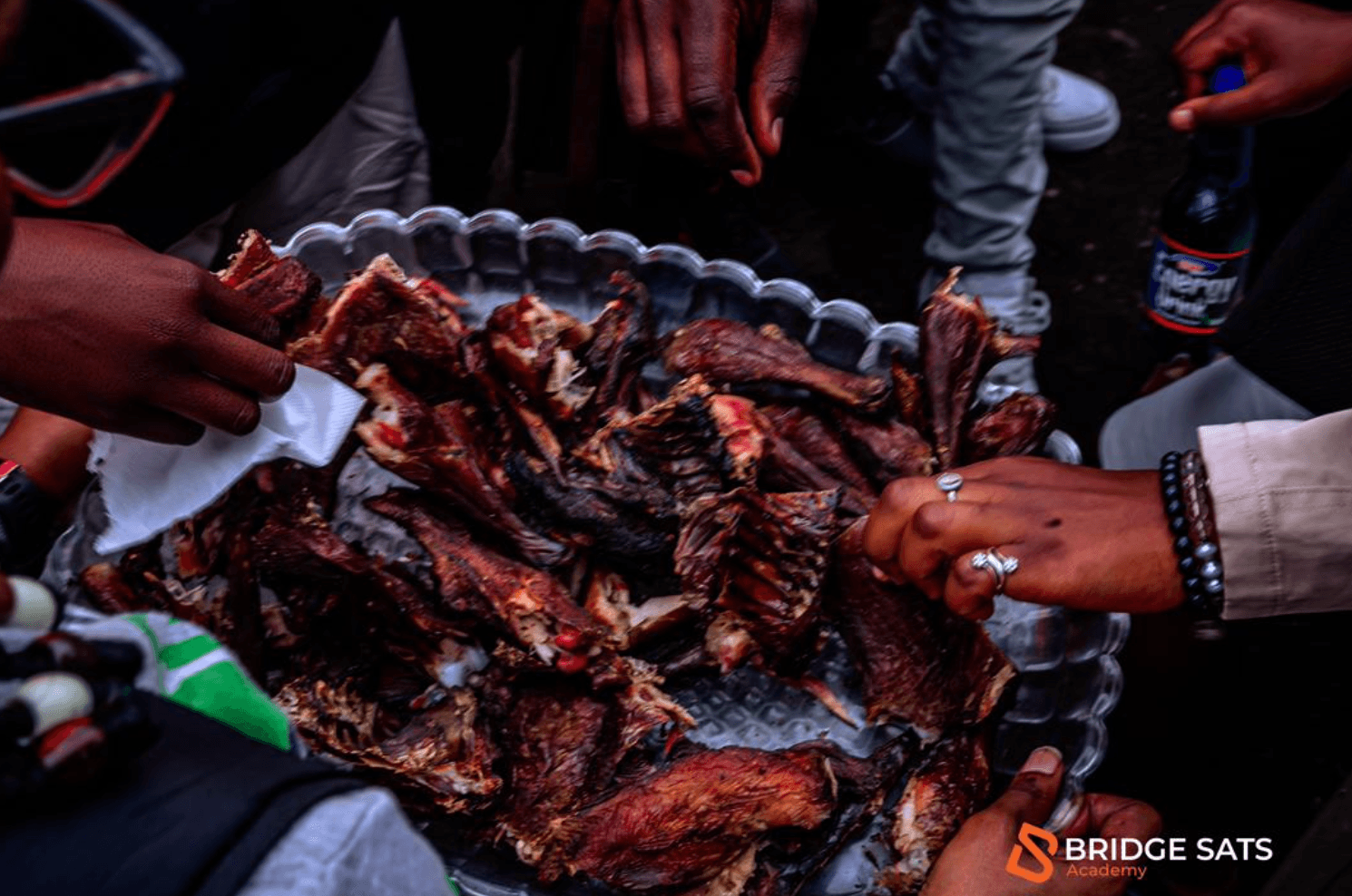 Participants sharing a meal of chicken purchased with Bitcoin at the University of Goma's Green Lake Campus during a Bridge Sats Bitcoin adoption event in April 2026