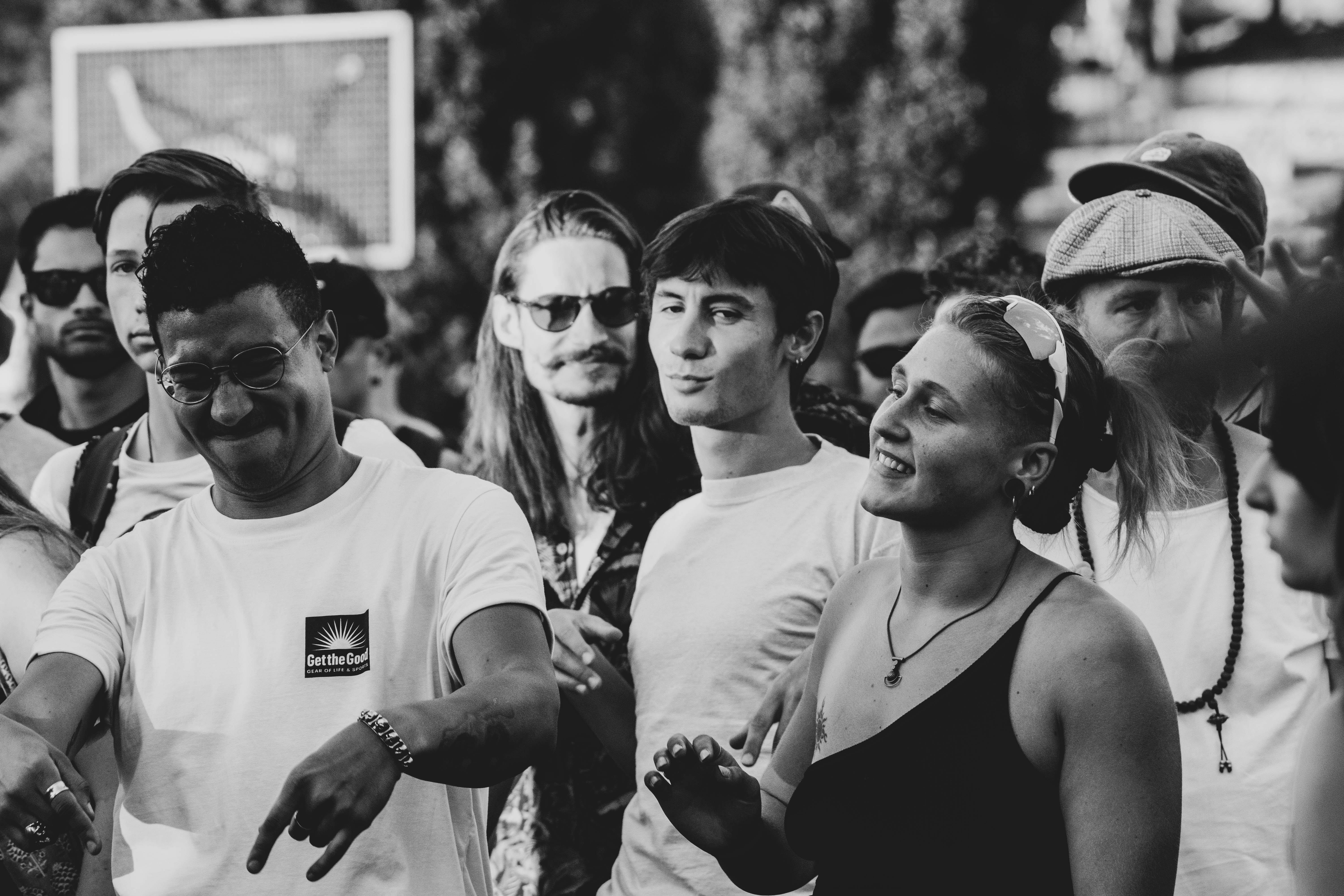 People dancing freely outdoors at a community gathering, expressing movement, connection, and nervous system regulation through embodied play and rhythm.