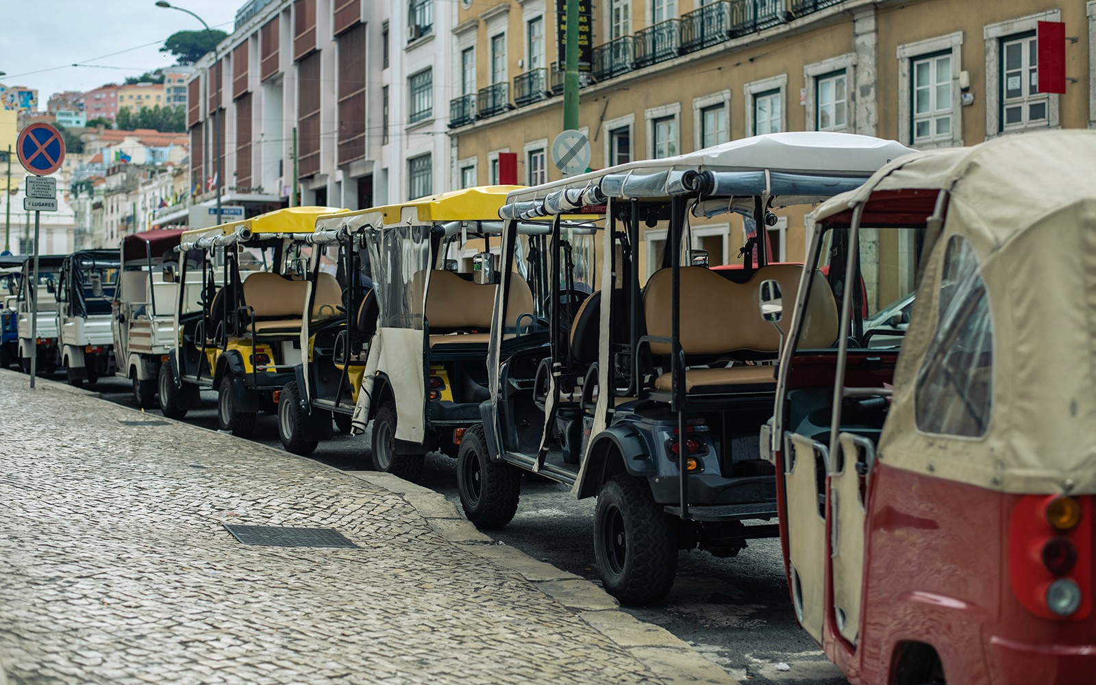 电动三轮车整齐地排列在鹅卵石街道上,准备开始半天的观光之旅。