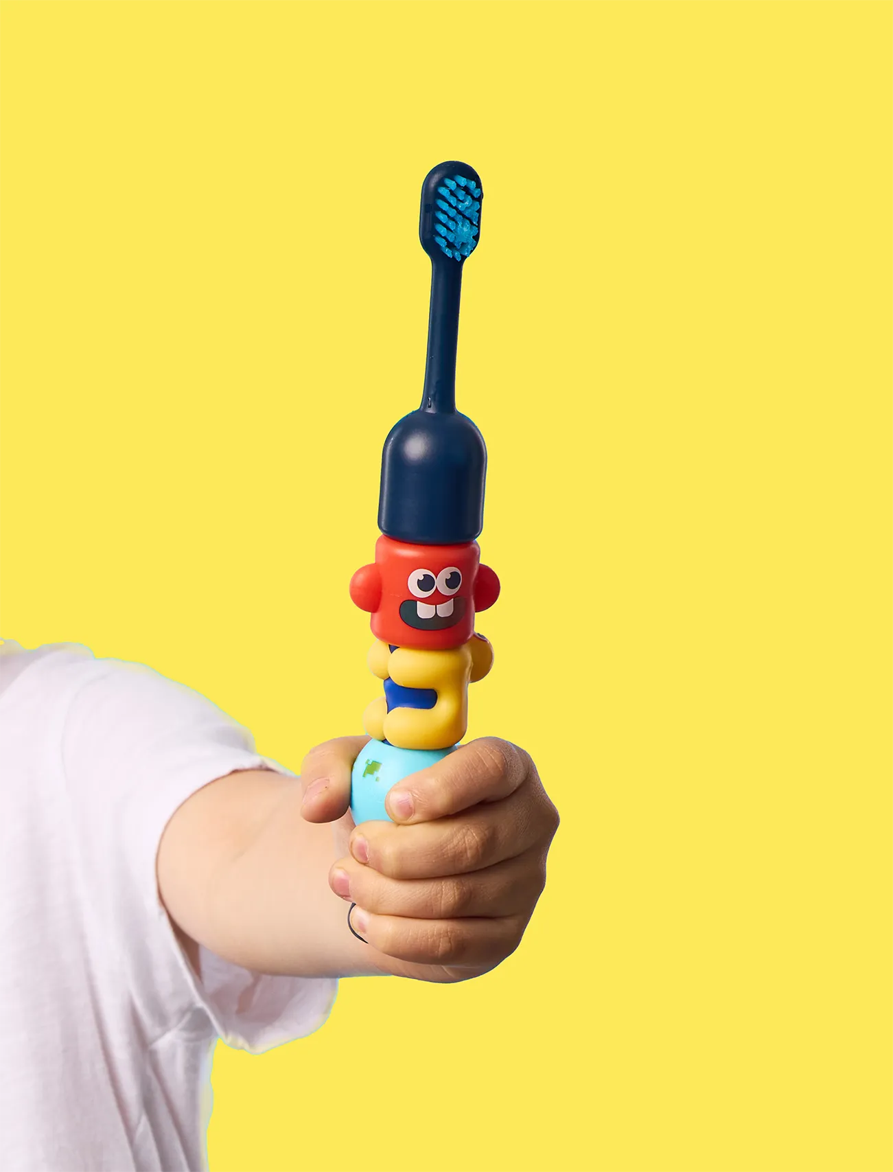 BABSY Build-A-Brush children's toothbrush held against a yellow background