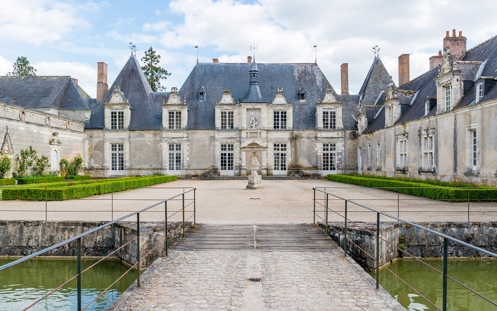 Château de Chambord entrance with bridge and manicured gardens on a sunny day.