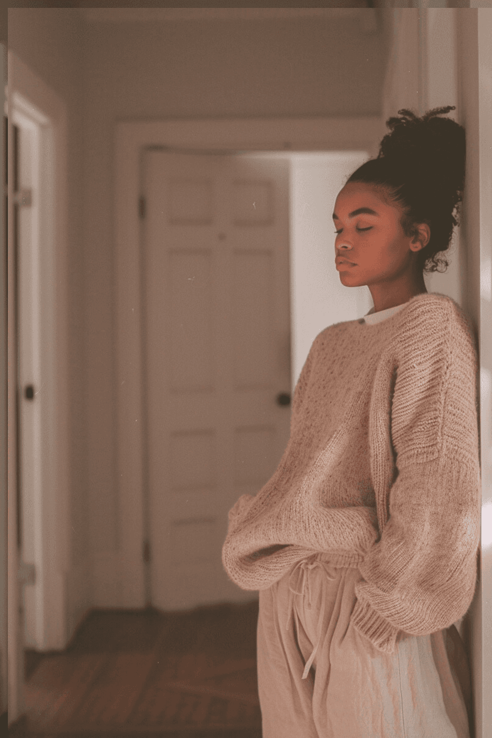 Postpartum mother leaning against wall with eyes closed, feeling worried about low milk supply in early breastfeeding