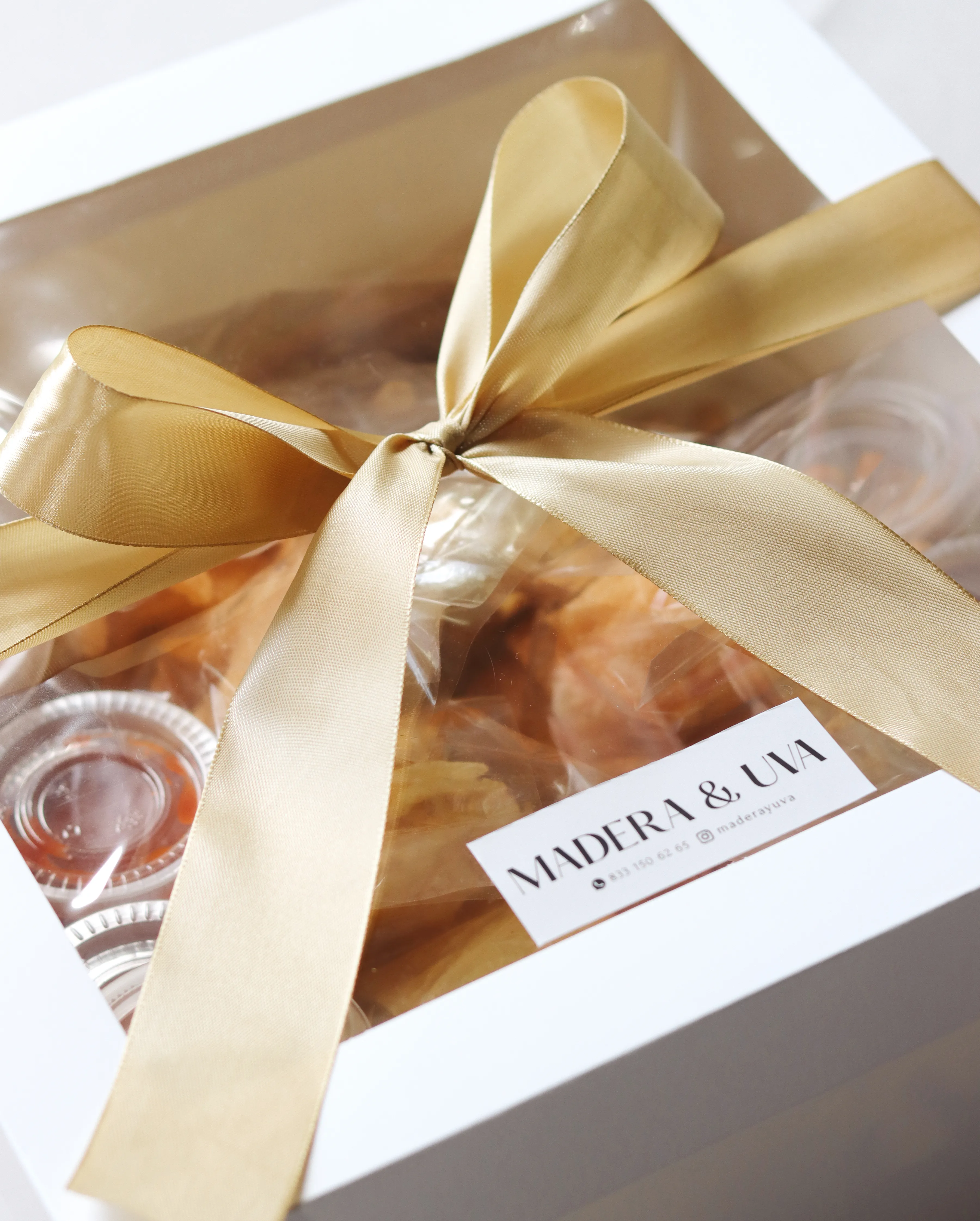 Caja de regalo con moño dorado y productos gourmet