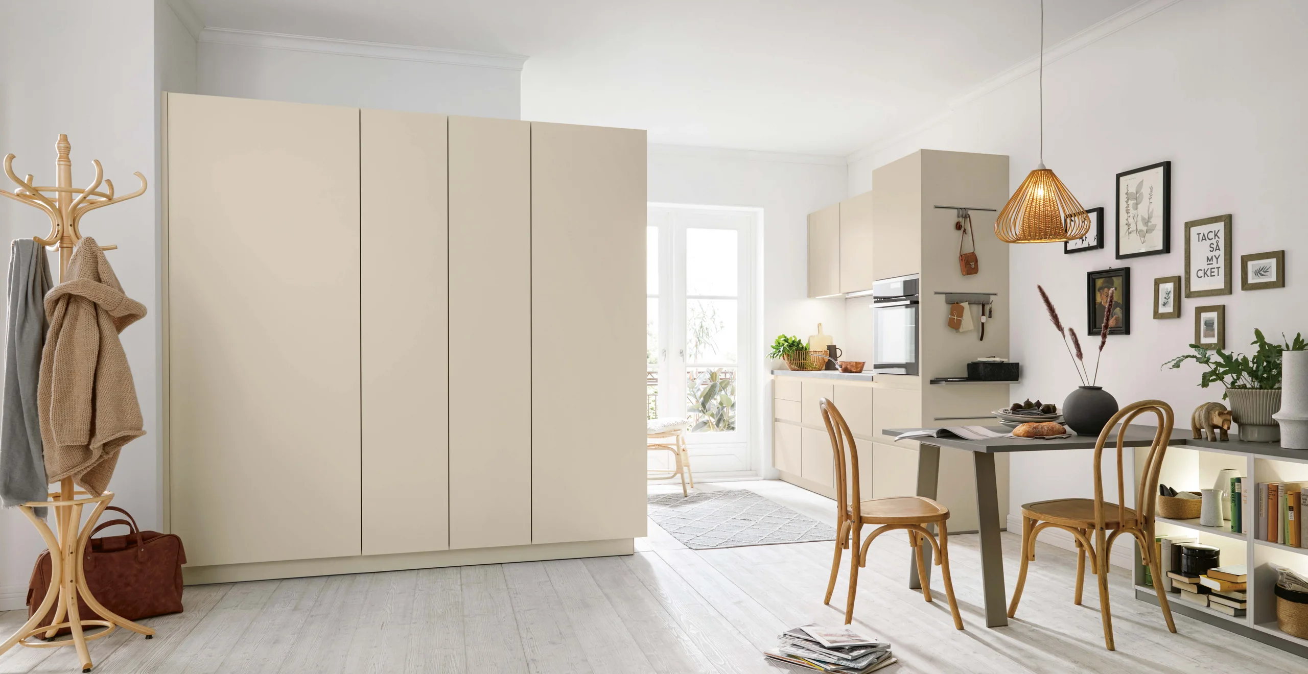 Cuisine ouverte compacte Schüller NOVA aux façades beige clair, avec table pour deux et rangements